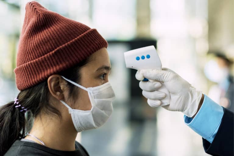 woman medical mask getting her temperature measured by electronic thermometer
